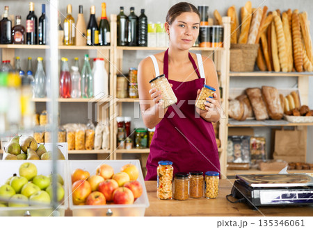 Young female seller offering beans in grocery store 135346061