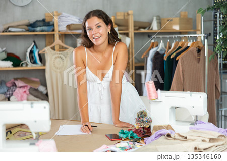 Dressmaker draws a model of clothes on paper in a workshop 135346160