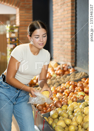 Young female shopper selects and buys potatoes in supermarket 135346187