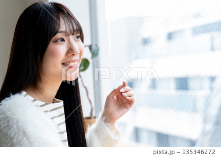 窓の外を眺めながらリラックスして微笑む女性 135346272