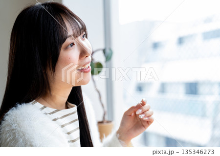 窓の外を眺めながらリラックスして微笑む女性 窓の外を眺めながらリラックスして微笑む女性 135346273