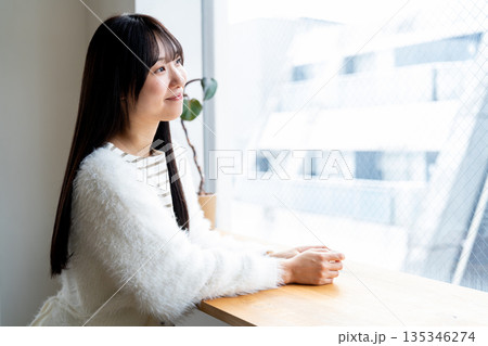 窓の外を眺めながらリラックスして微笑む女性 窓の外を眺めながらリラックスして微笑む女性 135346274