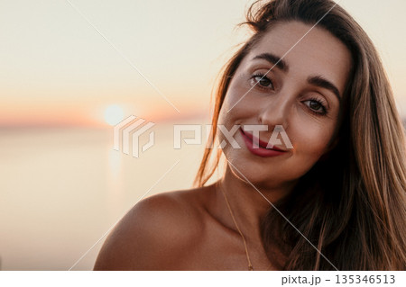 Woman Sunset Portrait Beautiful young woman smiling at the camera during golden hour by the ocean with soft bokeh background 135346513