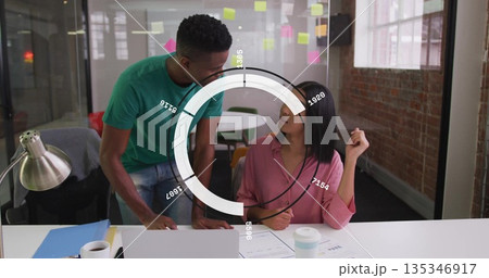Leaning man and seated coworker discussing data at office, with laptop, sticky notes, info overlay Leaning man and seated coworker discussing data at office, with laptop, sticky notes, info overlay 135346917