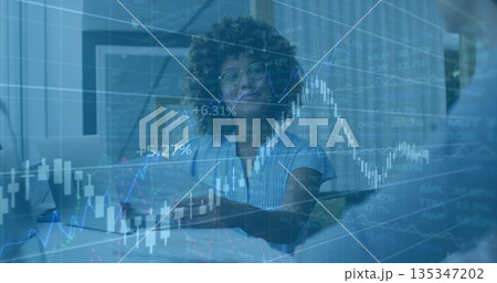 Woman in blouse discussing market trends at conference table, with laptop notebook charts Woman in blouse discussing market trends at conference table, with laptop notebook charts 135347202