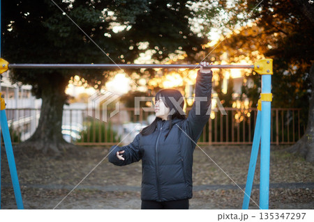 冬の夕方の住宅地の公園で楽しく遊んでいる女子高校生の姿	 135347297