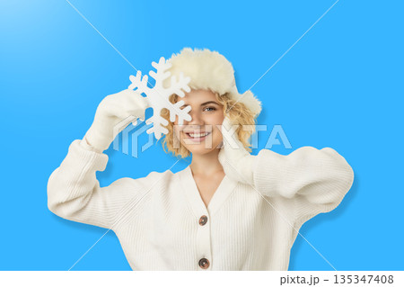 Happy woman in winter wear holds a snowflake Happy woman in winter wear holds a snowflake 135347408