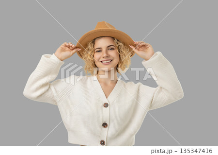 Young woman in a white sweater and tan hat smiling Young woman in a white sweater and tan hat smiling 135347416