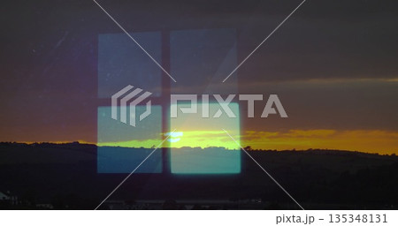 Reflecting four-pane digital grid through glass window over hills at sunset, with hill silhouettes 135348131