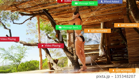 Adjusting adult woman showering under bamboo canopy on deck, with bathtub and notification overlays 135348207