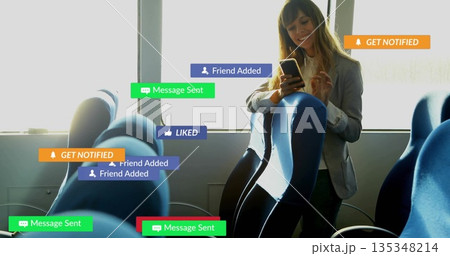 Businesswoman tapping smartphone in bus aisle by window with notification overlays, copy space 135348214