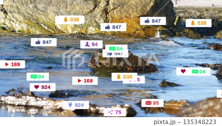 Digital notification icons hovering over rocky shoreline at water's edge, combining nature and tech 135348223