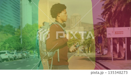Standing man wearing maroon sweater, jeans on sidewalk, holding smartphone, backpack and headphones Standing man wearing maroon sweater, jeans on sidewalk, holding smartphone, backpack and headphones 135348273