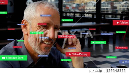 Man in polo shirt calling on smartphone, smiling at rooftop cafe table with floating digital labels 135348353