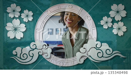 Posing mid adult Black woman wearing green cardigan in circular frame at studio, with floral motifs Posing mid adult Black woman wearing green cardigan in circular frame at studio, with floral motifs 135348498