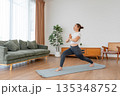 Happy young Asian woman practicing yoga and shoulder stretching  in living room at home 135348752