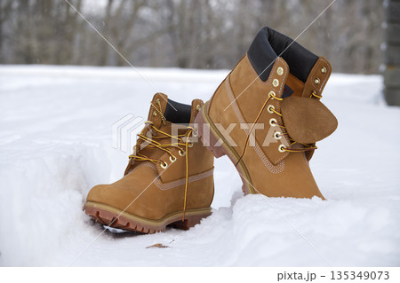 Iconic tan work boots with yellow laces stand in fresh winter snow 135349073