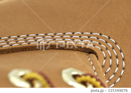 Close-up detail of tan leather boot stitching and eyelets, showcasing craftsmanship 135349076