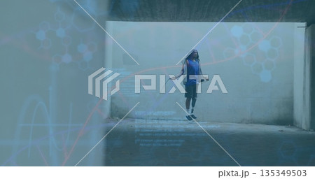 Jumping man wearing sleeveless hooded sweatshirt and shorts in concrete underpass, with jump rope Jumping man wearing sleeveless hooded sweatshirt and shorts in concrete underpass, with jump rope 135349503