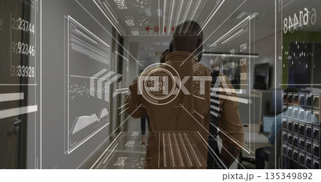 Talking man in brown jacket holding smartphone in tech office corridor, with floating data panels 135349892