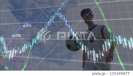 Male soccer player wearing blue jersey dribbling soccer ball against sky, with stock chart overlay Male soccer player wearing blue jersey dribbling soccer ball against sky, with stock chart overlay 135349977