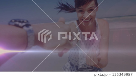 Running mid adult woman wearing sundress holding hand on beach, with wristwatch, sunscreen streak 135349987