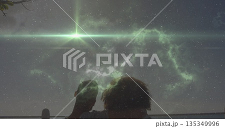 Leaning couple gazing at star-filled sky from rooftop terrace, with metal railing and green nebula 135349996