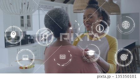 Hugging mother and daughter sharing warm embrace in modern kitchen, with digital icons overlay 135350101