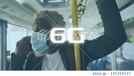 Standing commuter gripping yellow pole and adjusting mask strap on transit bus, with backpack 135350137