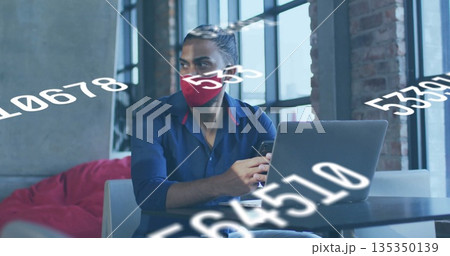 Analyzing man in red mask using laptop and smartphone in coworking lounge with numerical overlays Analyzing man in red mask using laptop and smartphone in coworking lounge with numerical overlays 135350139