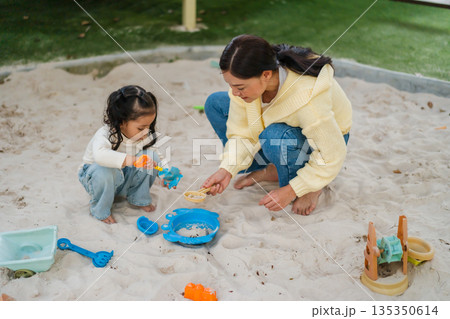 mother and child girl playing sand with toy on playground mother and child girl playing sand with toy on playground 135350614