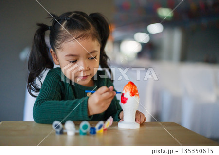 child girl painting plaster statue on table child girl painting plaster statue on table 135350615