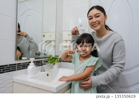 mother teaching girl child to brushing teeth in bathroom mother teaching girl child to brushing teeth in bathroom 135350629