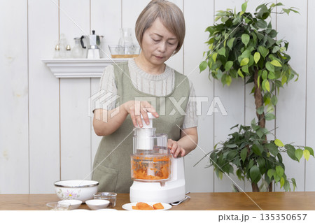 キッチンでフードプロセッサーを使い料理をするシニア女性 キッチンでフードプロセッサーを使い料理をするシニア女性 135350657