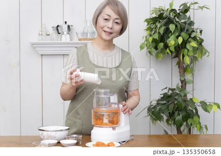 キッチンでフードプロセッサーを使い料理をするシニア女性 キッチンでフードプロセッサーを使い料理をするシニア女性 135350658