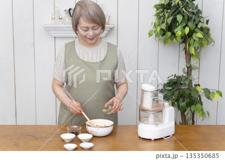 キッチンでフードプロセッサーを使い料理をするシニア女性 キッチンでフードプロセッサーを使い料理をするシニア女性 135350685