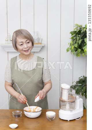 キッチンでフードプロセッサーを使い料理をするシニア女性 キッチンでフードプロセッサーを使い料理をするシニア女性 135350692