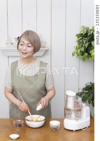 キッチンでフードプロセッサーを使い料理をするシニア女性 キッチンでフードプロセッサーを使い料理をするシニア女性 135350693