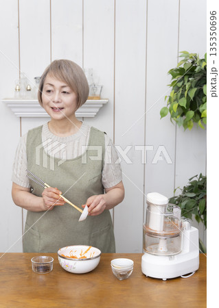 キッチンでフードプロセッサーを使い料理をするシニア女性 キッチンでフードプロセッサーを使い料理をするシニア女性 135350696