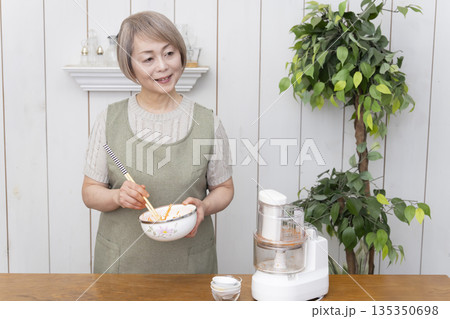 キッチンでフードプロセッサーを使い料理をするシニア女性 キッチンでフードプロセッサーを使い料理をするシニア女性 135350698