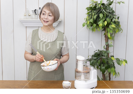 キッチンでフードプロセッサーを使い料理をするシニア女性 キッチンでフードプロセッサーを使い料理をするシニア女性 135350699