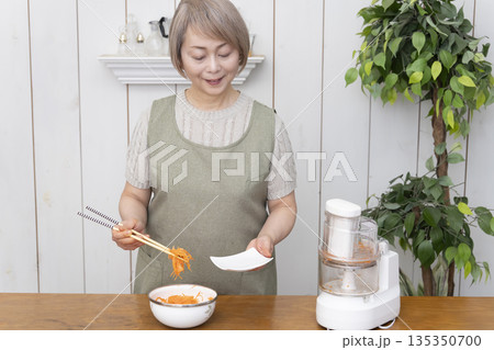 キッチンでフードプロセッサーを使い料理をするシニア女性 キッチンでフードプロセッサーを使い料理をするシニア女性 135350700
