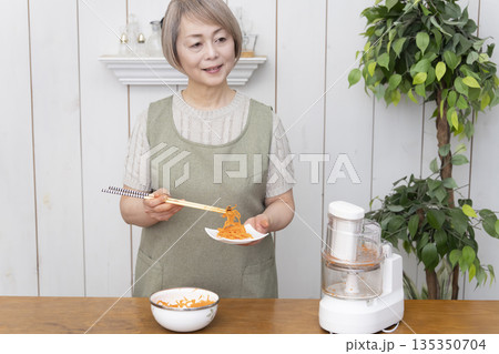 キッチンでフードプロセッサーを使い料理をするシニア女性 キッチンでフードプロセッサーを使い料理をするシニア女性 135350704