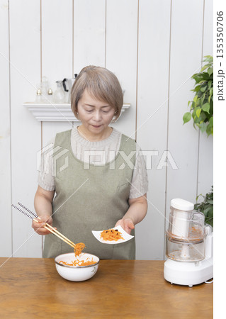 キッチンでフードプロセッサーを使い料理をするシニア女性 キッチンでフードプロセッサーを使い料理をするシニア女性 135350706