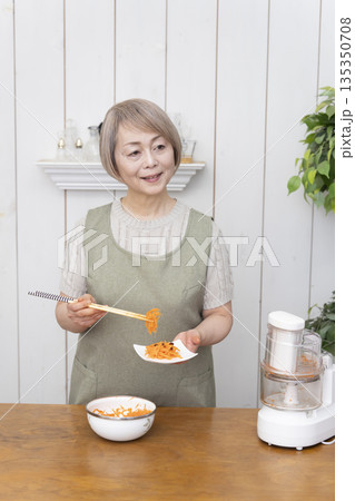 キッチンでフードプロセッサーを使い料理をするシニア女性 キッチンでフードプロセッサーを使い料理をするシニア女性 135350708