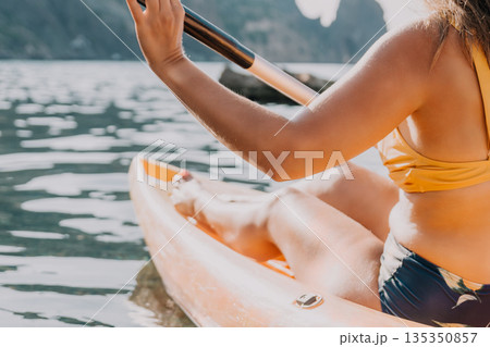 Kayaking Woman Paddle Water - Woman kayaking in scenic waters with a paddle in hand on a sunny day. 135350857
