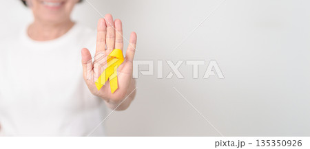 Elderly with Yellow Ribbon for concept of yellow September, Suicide prevention day, Childhood, July Sarcoma, March Endometriosis awareness month , support survivor. Healthcare and World Cancer day 135350926