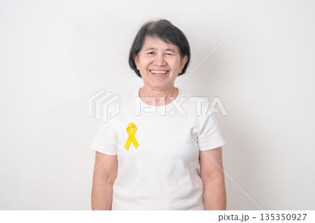 Elderly with Yellow Ribbon for concept of yellow September, Suicide prevention day, Childhood, July Sarcoma, March Endometriosis awareness month , support survivor. Healthcare and World Cancer day 135350927