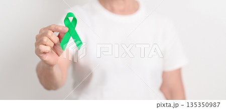 Elderly with Green Ribbon for concept of March world Bipolar disorder day, Cerebral Palsy Awareness month, kidney disease Cancer and Traumatic Brain Injury, TBI. Healthcare and world cancer day Elderly with Green Ribbon for concept of March world Bipolar disorder day, Cerebral Palsy Awareness month, kidney disease Cancer and Traumatic Brain Injury, TBI. Healthcare and world cancer day 135350987