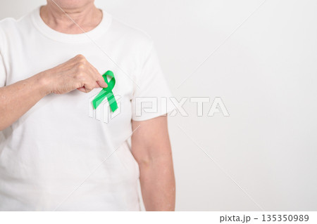 Elderly with Green Ribbon for concept of March world Bipolar disorder day, Cerebral Palsy Awareness month, kidney disease Cancer and Traumatic Brain Injury, TBI. Healthcare and world cancer day Elderly with Green Ribbon for concept of March world Bipolar disorder day, Cerebral Palsy Awareness month, kidney disease Cancer and Traumatic Brain Injury, TBI. Healthcare and world cancer day 135350989